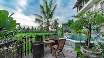 A wooden deck with wicker furniture, a small table, and a potted plant.