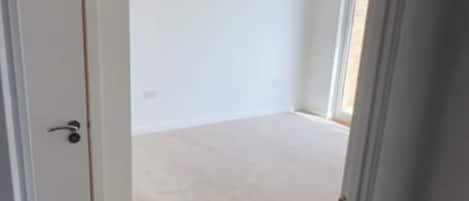 Une pièce avec une porte, un interrupteur et un luminaire au plafond.