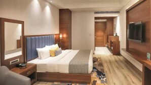 Una habitación de hotel con una cama grande, mesitas de noche, televisión y un espejo.
