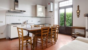 Uma cozinha com mesa e cadeiras, fogão, armários e janela com vista para área verde.