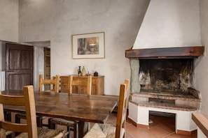 Un comedor con una mesa y sillas de madera, una chimenea y un cuadro en la pared.