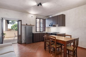 A compact kitchen with a dining area, a refrigerator, a microwave, and a stove.