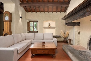 A living room with a sofa, a coffee table, a fireplace, and a clock.
