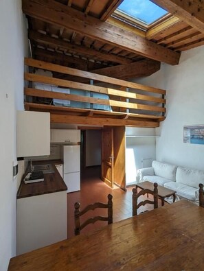 Un espacio tipo loft con techo de madera, una mesa de comedor y un sofá blanco.