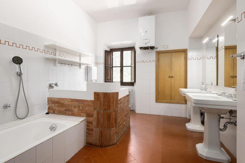A bathroom with a bathtub, a shower, a wooden door, and a white sink.