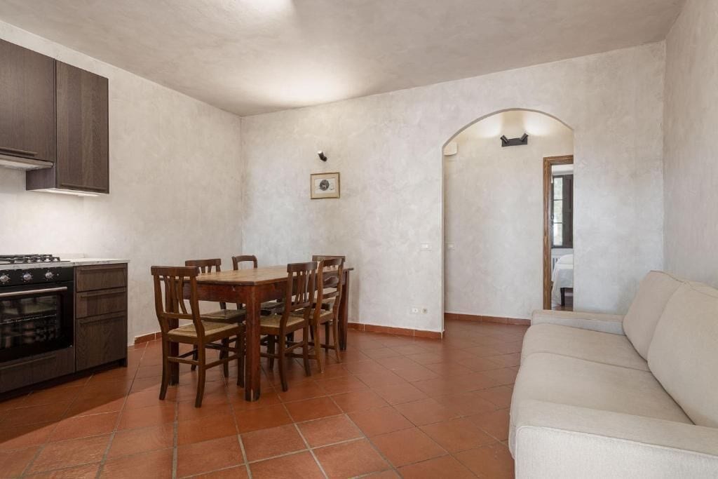 Una cocina con una mesa de comedor y sillas, un sofá y piso de baldosas.