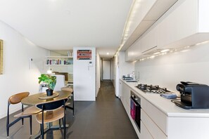 Eine moderne Küche mit Herd, Kaffeemaschine und einem Essbereich mit Tisch und Stühlen.