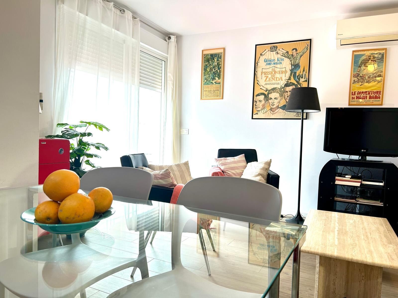 A living room with a glass table, a red cabinet, a sofa, and a television.
