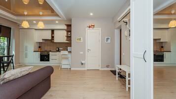A modern kitchen with white cabinets, a dining area with a sofa, and a hallway leading to another room.