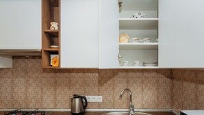 Eine Küche mit Gasherd, einem Edelstahl-Spülbecken und einem Schrank mit Geschirr.