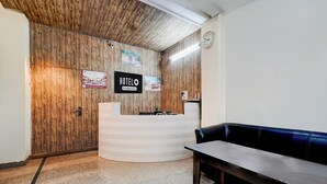 A reception desk with a wooden backdrop, a clock, and a blue bench.