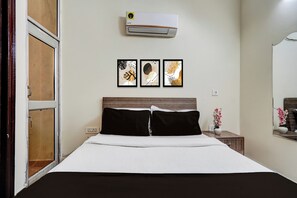 A hotel room with a bed, a wall-mounted air conditioner, and three framed artworks above the bed. - Hotel O Railway Station Road Formerly (Alwar)