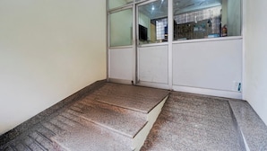 Una habitación con un ventanal grande, una puerta y un escalón pequeño que conduce a un nivel inferior.