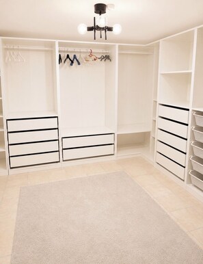 Un vestidor con estantes abiertos, espacio para colgar ropa y cajones.