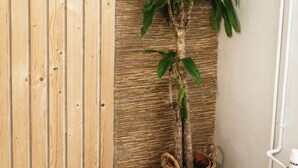 A room with a wooden panel wall, a woven wall panel, and a potted plant in a basket.