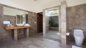 Un baño con un espejo grande, dos lavamanos, un inodoro y una zona de ducha.