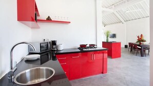 Una cocina moderna con armarios rojos, un lavamanos de acero inoxidable y una zona de comedor con una pared de acento roja.