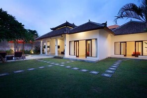A modern house with a covered patio, a lawn, and a stone pathway. - Villa Alma (Badung)