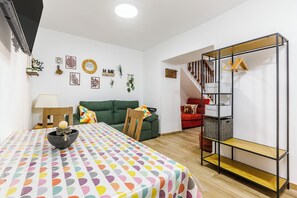 Una stanza con un letto, un divano, un tavolo da pranzo, una scala e una parete con diverse decorazioni.