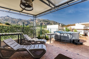A covered outdoor area with lounge chairs, a barbecue grill, and a view of mountains. - The Foosball House: Full House in the ChillOut Village, Pool, Views (Villanueva del Rosario)