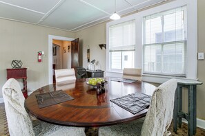 A dining area with a round wooden table, chairs, and a bowl of green apples. - Walk to Shops & Restaurants! NOLA Extended Stay (New Orleans)