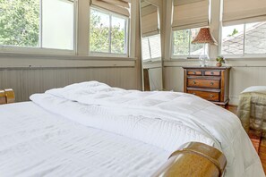A bedroom with a large bed, a dresser, and a window with a view of greenery. - Walk to Shops & Restaurants! NOLA Extended Stay (New Orleans)