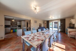 Un comedor amplio con una mesa larga, sillas y una cocina al fondo.