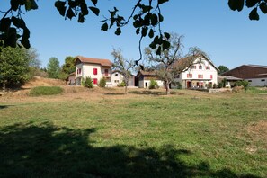Propiedad rural con varias construcciones, un campo cubierto de hierba y árboles.
