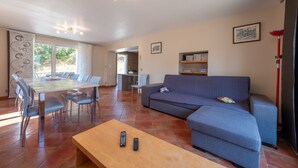 Uma sala de estar moderna com um sofá, uma mesa de centro e um canto de jantar com cadeiras e mesa.