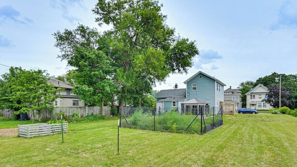 A residential area with houses, a fenced yard, and a clear sky.