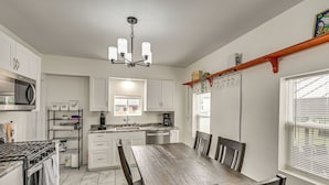 A modern kitchen with white cabinets, a granite countertop, a built-in oven, and a dining area with a wooden table and chairs.