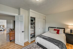 Un dormitorio con cama, mesita de noche y armario abierto con ropa colgada.