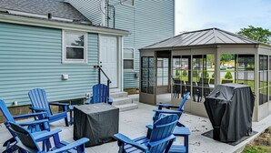 A patio area with blue Adirondack chairs, a covered table, and a gazebo with a view of the street.