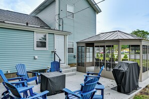 Un patio con sillas Adirondack azules, una mesa cubierta y un pabellón con vista a la calle.