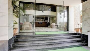 Un hall d’hôtel comprenant un comptoir d’accueil, un espace salon et un escalier menant à l’étage supérieur.