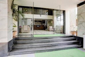A hotel lobby with a reception desk, seating area, and a staircase leading to an upper floor.
