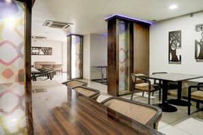 A restaurant with a long wooden counter, multiple tables, and chairs.
