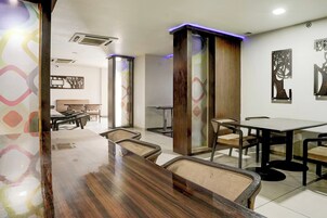 A restaurant with a long wooden counter, multiple tables, and chairs.