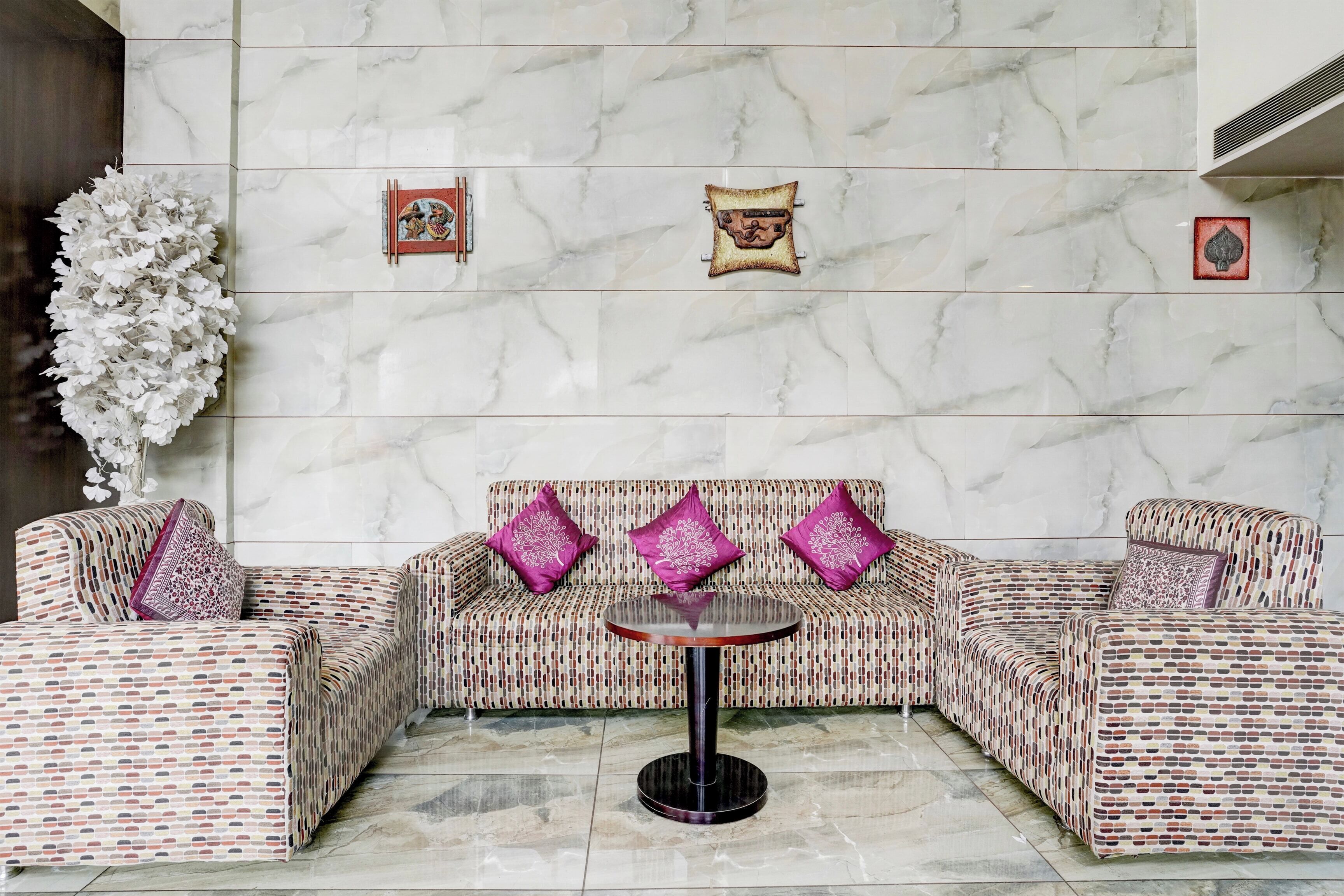 Un área de estar con un sofá estampado, una mesa redonda y cojines decorativos.
