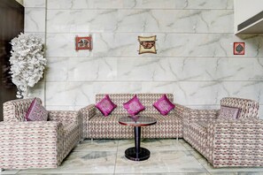 Un coin salon comprenant un canapé à motifs, une table ronde et des coussins décoratifs.