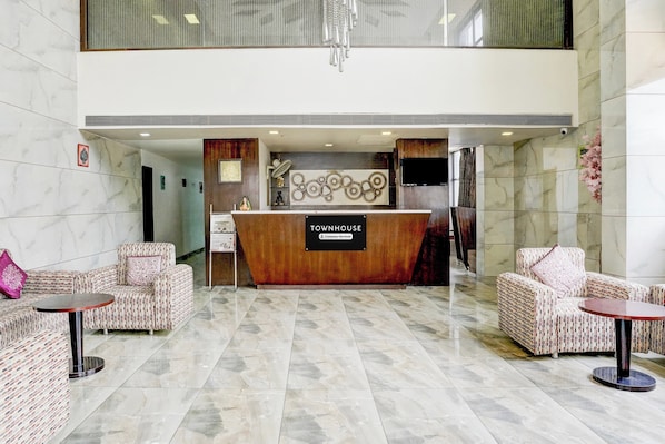 A reception area with a wooden reception desk, two sofas with patterned upholstery, and a chandelier.