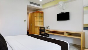 Une chambre d’hôtel comprenant un lit, un bureau, une chaise, une télévision et une armoire.