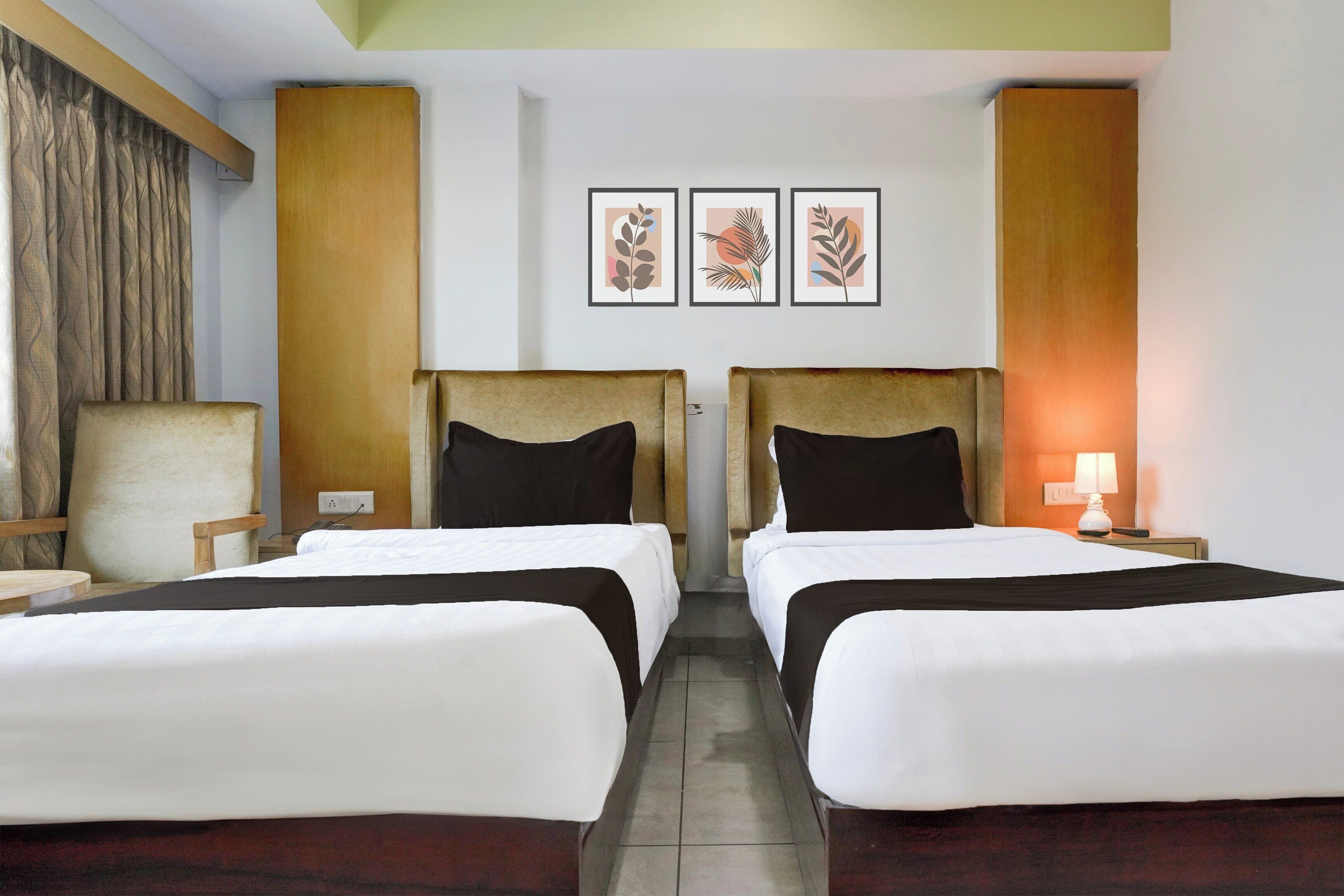 A hotel room with two beds, a chair, a desk, and a lamp.