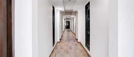 A long, narrow hallway with white walls and a wooden floor.
