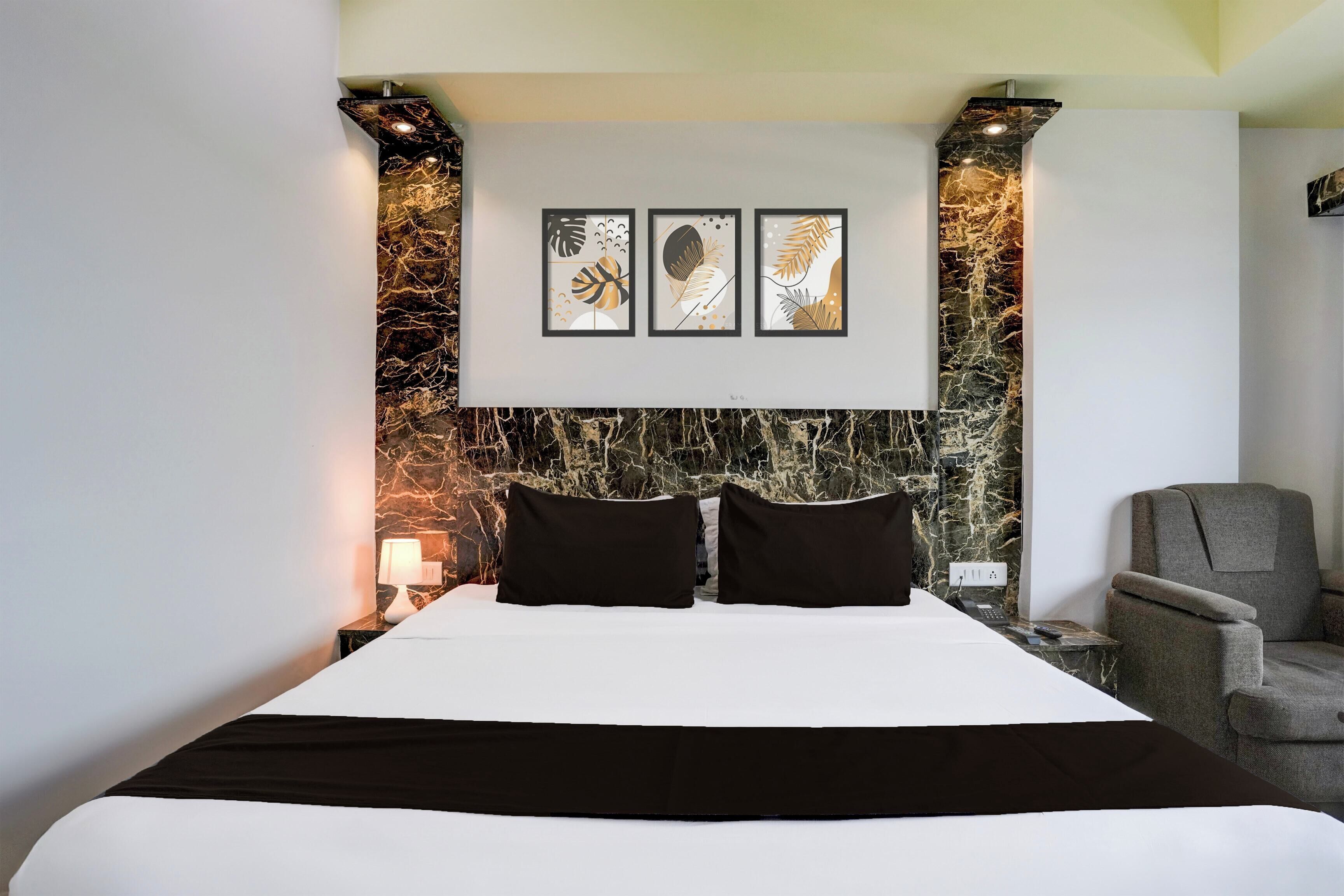 Habitación de hotel con cama, una silla, una mesita de noche y una pared con un diseño tipo mármol.