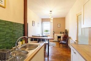 A kitchen with a green tiled backsplash, a wooden dining table, and a fireplace. - Serene 2BDR Flat Near Edinburgh Old Town (Edinburgh)