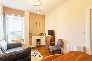 A living room with a fireplace, a television, and a sofa. - Serene 2BDR Flat Near Edinburgh Old Town (Edinburgh)