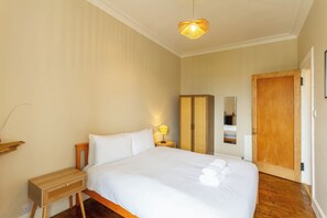 A hotel room with a bed, bedside table, lamp, wardrobe, and a door. - Serene 2BDR Flat Near Edinburgh Old Town (Edinburgh)
