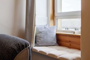 Ein Zimmerwinkel mit einem Fenster, einem Kissen und einem Möbelstück.