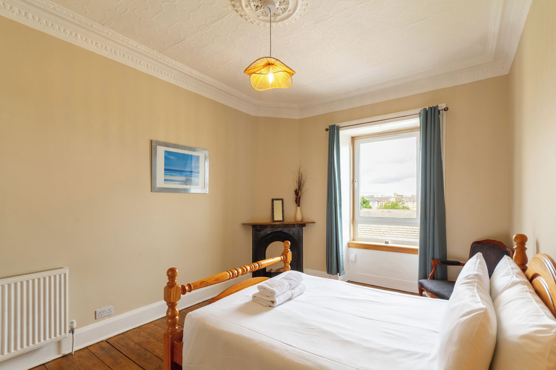 A bedroom with a bed, a fireplace, a window with curtains, and a view of the outside.